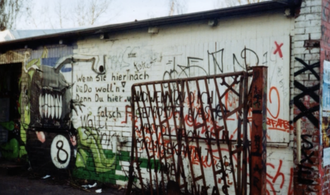 Wand mit vielen Graffiti und einem Metalltor