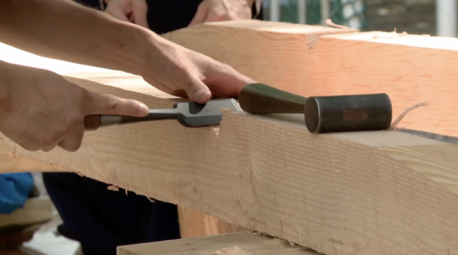 Holzbalen der mit Stecheisen bearbeitet wird